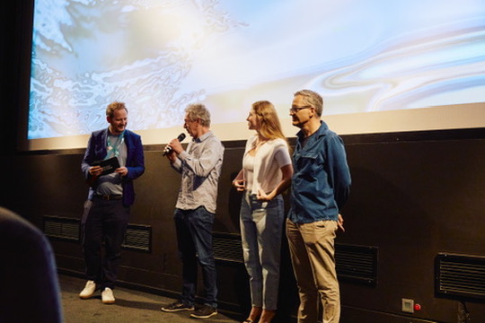 Celine Wempe during a presentation at the Munich Film Festival 2023, introducing La Práctica on stage, wearing a formal dress and engaging with the festival audience.